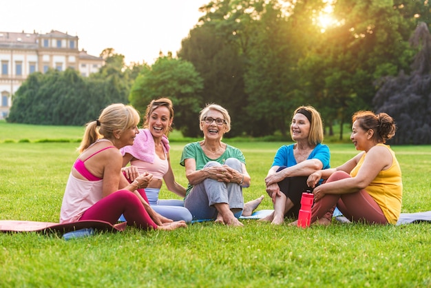 Grupo multiétnico de mujeres mayores entrenando en el parque con instructor de fitness - Ancianos activos haciendo deporte en la naturaleza