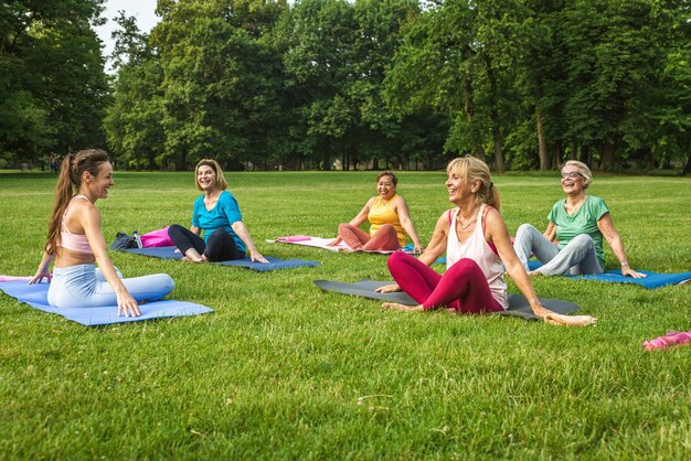 Grupo multiétnico de mujeres mayores entrenando en el parque con instructor de fitness - Ancianos activos haciendo deporte en la naturaleza