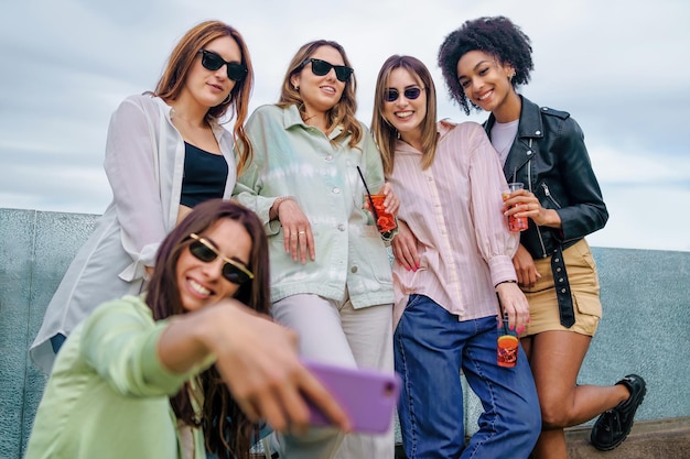 Grupo multirracial de amigas tomando selfies en la calle