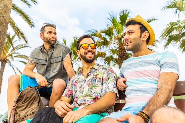 Grupo multirracial de amigos juntos en un banco junto al mar en Barcelona