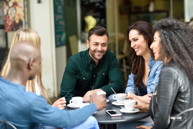 Grupo multirracial de cinco amigos tomando un café juntos