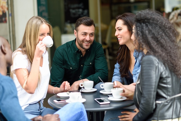 Grupo multirracial de cinco amigos tomando un café juntos