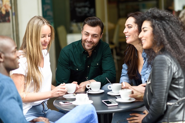 Grupo multirracial de cinco amigos tomando un café juntos