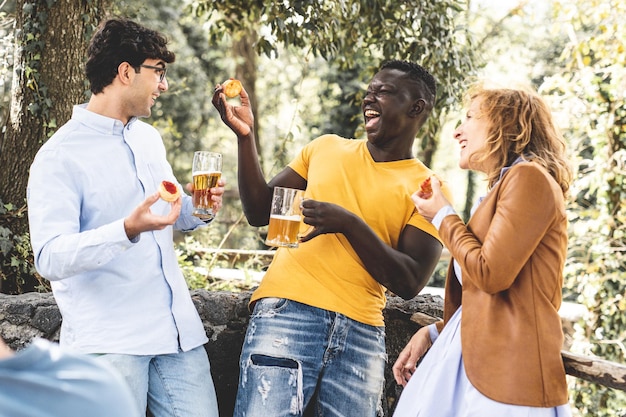 Grupo multirracial de amigos rindo e se divertindo na festa grupo de faixa etária mista comemorando algo comendo lanche e bebendo cervejas