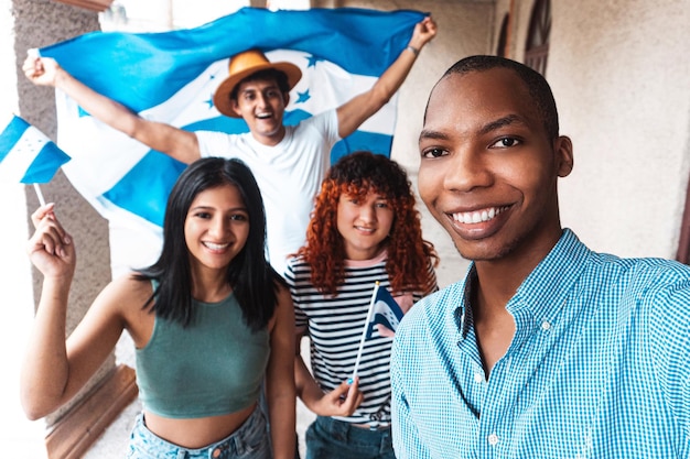 Grupo multirracial de amigos tirando uma selfie comemorando a independência de Honduras