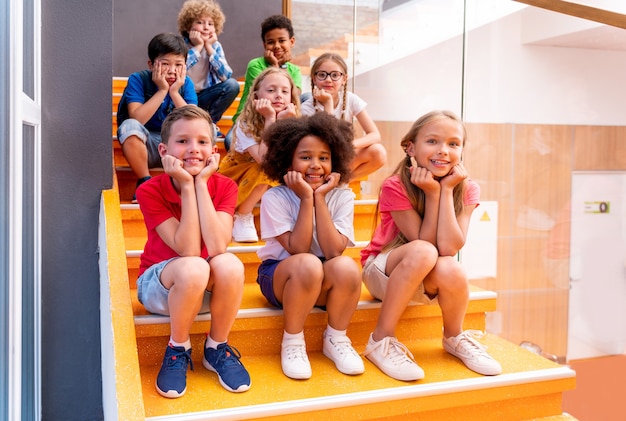 Grupo multirracial de crianças na escola primária - alunos brincalhões aproveitando o tempo da escola e as aulas com o professor e os colegas de classe