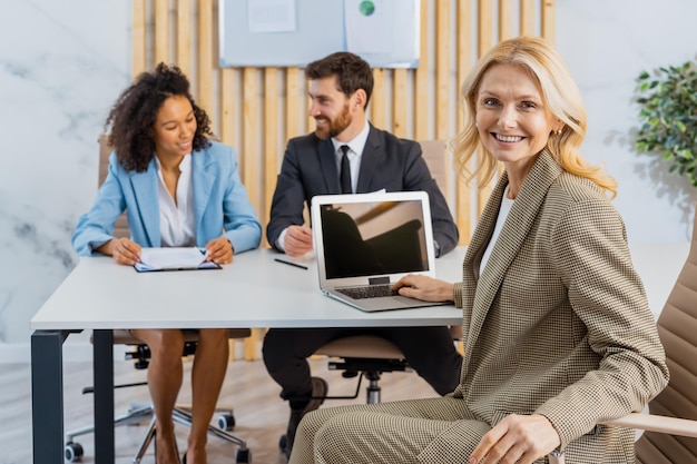 Grupo multirracial de empresários com vestido elegante sentado na mesa do computador no escritório