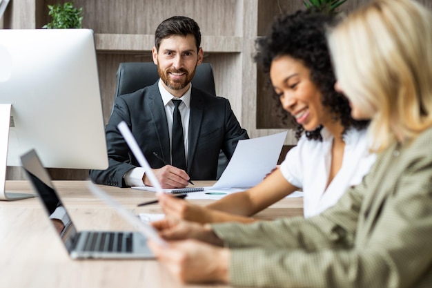 Grupo multirracial de empresários com vestido elegante sentado na mesa do computador no escritório