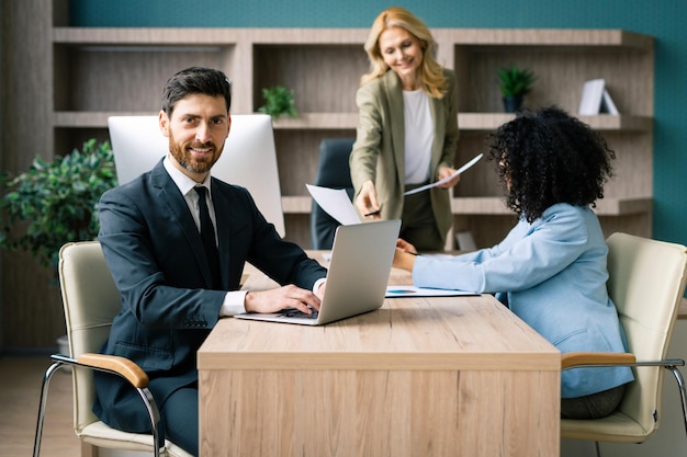 Grupo multirracial de empresários com vestido elegante sentado na mesa do computador no escritório