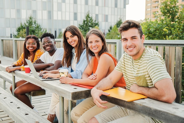 Grupo multirracial de estudantes adolescentes felizes olhando para a câmera sorrindo relaxados juntos do lado de fora