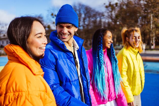 Foto grupo multirracial de jovens amigos reunidos ao ar livre no inverno