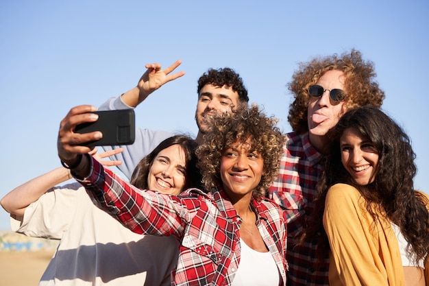 Grupo multirracial de jovens fazendo selfie