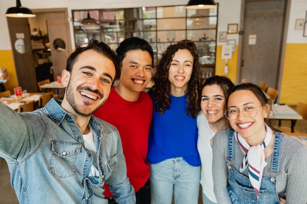 Grupo multirracial de jovens tomando selfie no interior