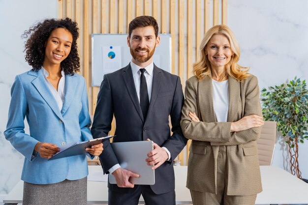 Grupo multirracial de empresarios con vestido elegante de pie en el escritorio de la computadora en la oficina