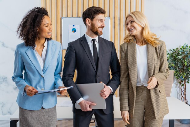 Grupo multirracial de empresarios con vestido elegante de pie en el escritorio de la computadora en la oficina