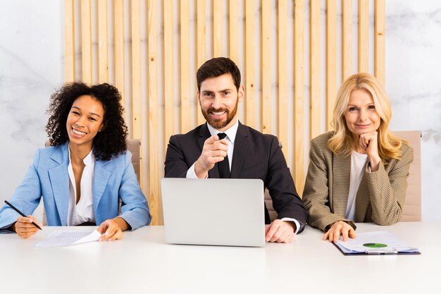 Grupo multirracial de empresarios con vestido elegante sentado en el escritorio de la computadora en la oficina