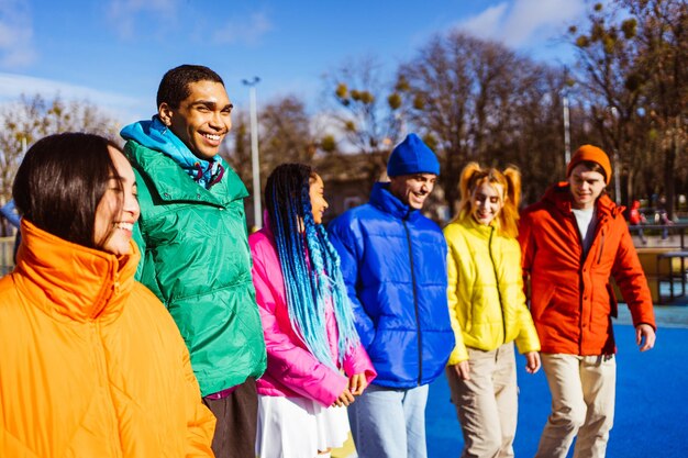 Grupo multirracial de jóvenes amigos reunidos al aire libre en invierno