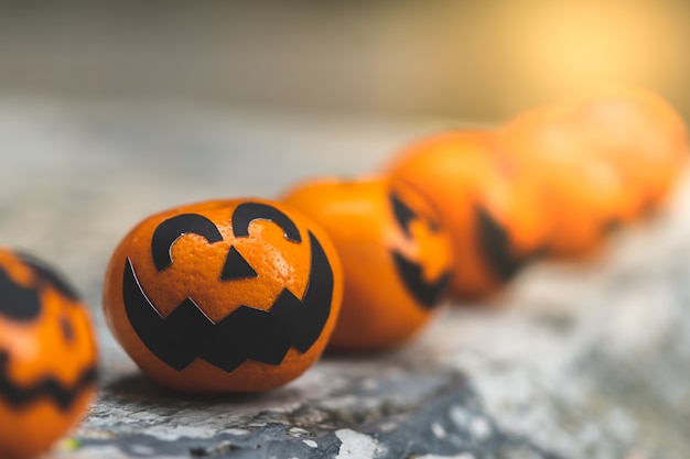 El grupo de naranjas hace frente a la pintura con asustadizo en día de la fiesta de Halloween en el lugar del jardín.