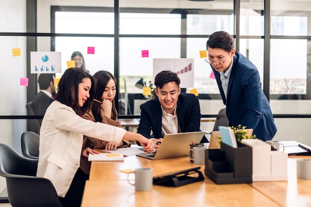 Grupo de negocios asiáticos reunidos y discutiendo el proceso financiero de análisis de proyectos de inicio de estrategia Plan de trabajo de gente de negocios exitoso y lluvia de ideas sobre ideas de marketing con computadora portátil en la oficina Trabajo en equipo