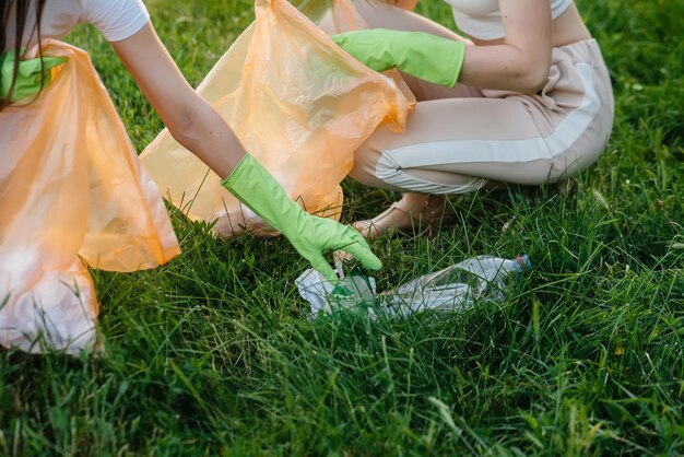 Un grupo de niñas con niños al atardecer se dedican a la recolección de basura en el parque. Cuidado del medio ambiente, reciclaje.