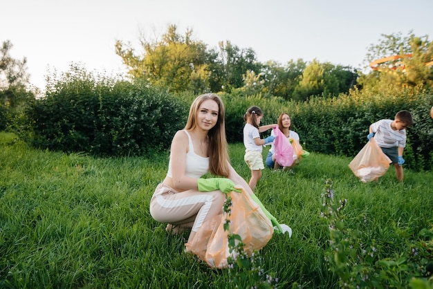 Un grupo de niñas con niños al atardecer se dedican a la recolección de basura en el parque. Cuidado del medio ambiente, reciclaje.