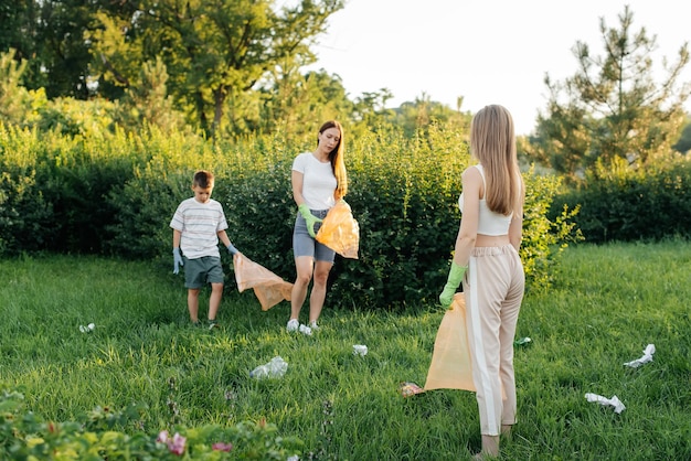 Un grupo de niñas con niños al atardecer se dedican a la recolección de basura en el parque Reciclaje de cuidado ambiental