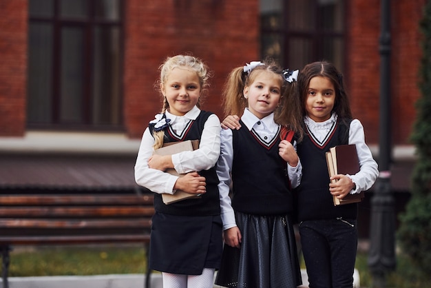 Pasado verdad Pelmel Grupo de niñas en uniforme escolar que está al aire libre junto al edificio  de educación. | Foto Premium