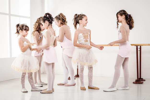 Grupo de niñas en vestidos tomando un descanso de la clase de ballet.