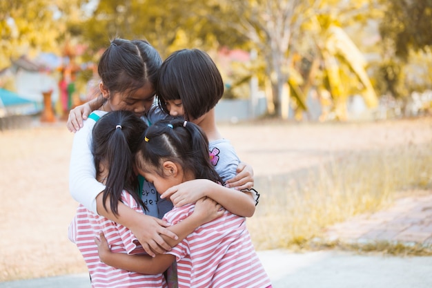 Grupo de niños asiáticos abrazando y jugando juntos con amor y diversión en el parque