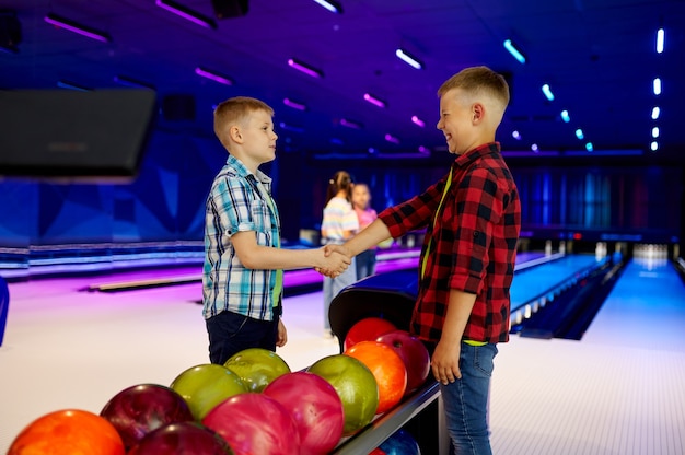 Grupo de niños en la bolera. Los niños se están preparando para marcar un strike. Niños y niñas divirtiéndose juntos en el centro de entretenimiento, pequeños jugadores de bolos