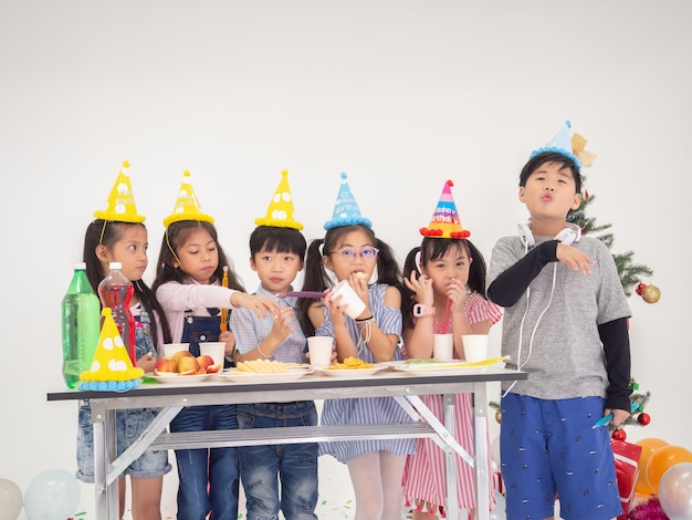 Grupo de niños celebran la fiesta y disfrutan de la diversión navideña juntos, los niños intercambian regalos.