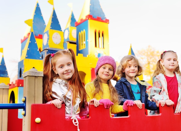 Un grupo de niños en edad preescolar juegan y sonríen en el fondo de un parque de atracciones para niños en forma de castillo de cuento de hadas