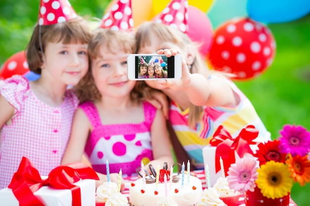 Foto grupo de niños felices celebrando cumpleaños niños divirtiéndose en el jardín de primavera