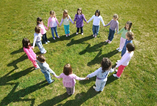 el grupo de niños felices se divierten y juegan en el concepto de educación preescolar al aire libre de jardín de infantes con el maestro