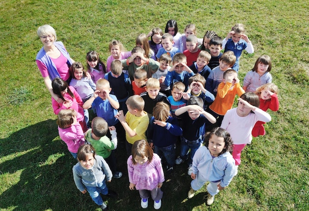 el grupo de niños felices se divierten y juegan en el concepto de educación preescolar al aire libre de jardín de infantes con el maestro