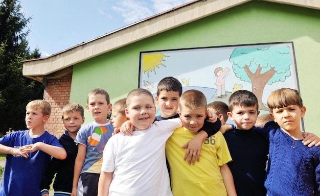 el grupo de niños felices se divierten y juegan en el concepto de educación preescolar al aire libre de jardín de infantes con el maestro