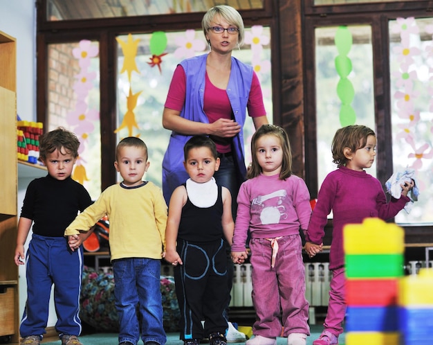 Foto el grupo de niños felices se divierten y juegan en el concepto de educación preescolar interior de jardín de infantes con el maestro