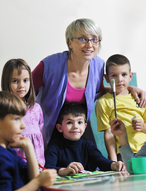 Foto el grupo de niños felices se divierten y juegan en el concepto de educación preescolar interior de jardín de infantes con el maestro