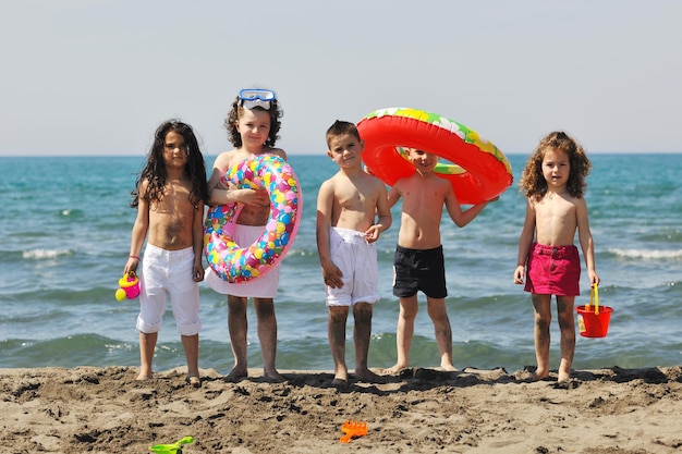 un grupo de niños felices se divierten en la playa mientras juegan con juguetes corriendo saltando