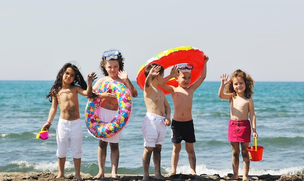 un grupo de niños felices se divierten en la playa mientras juegan con juguetes corriendo saltando