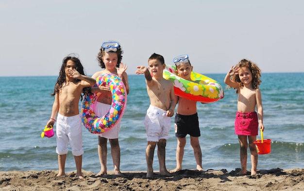 un grupo de niños felices se divierten en la playa mientras juegan con juguetes corriendo saltando