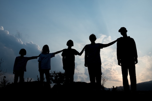 Grupo de niños felices jugando al atardecer, silueta