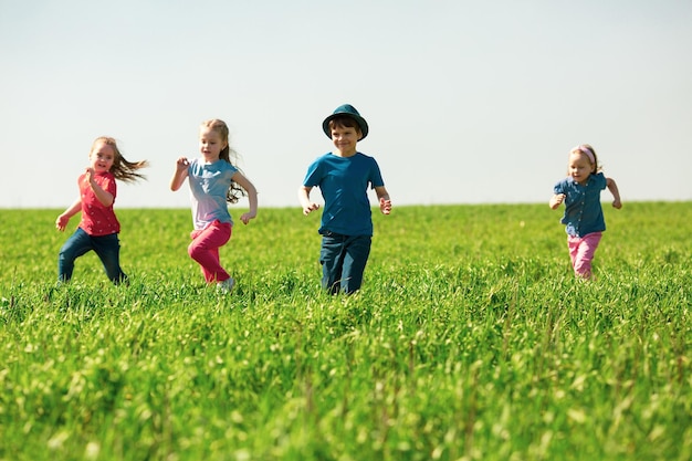 Foto un grupo de niños felices de niños y niñas corren en el parque sobre la hierba en un día soleado de verano el concepto de amistad étnica paz bondad infancia