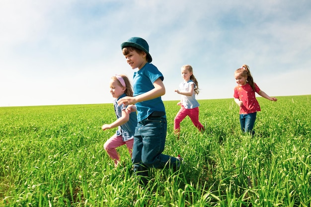 Foto un grupo de niños felices de niños y niñas corren en el parque sobre la hierba en un día soleado de verano el concepto de amistad étnica paz bondad infancia