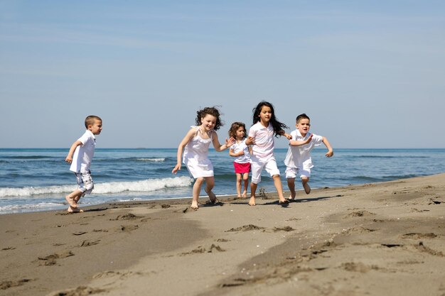 grupo de niños felices en la playa que se divierten y juegan