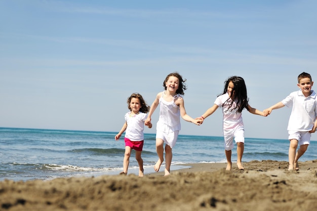 grupo de niños felices en la playa que se divierten y juegan