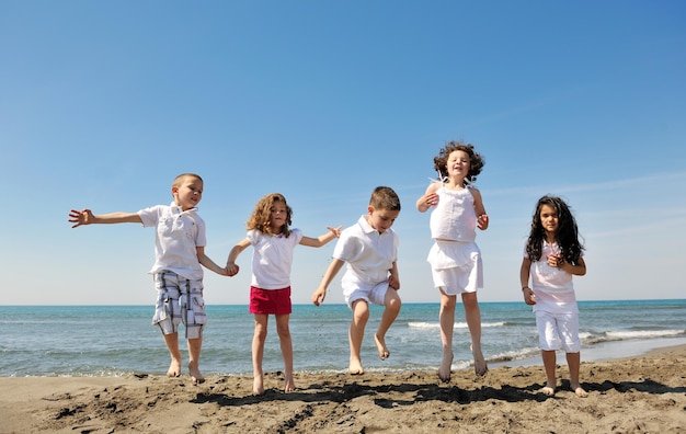 grupo de niños felices en la playa que se divierten y juegan