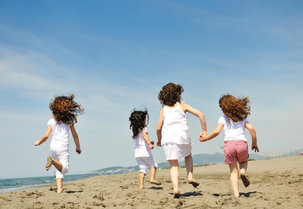 grupo de niños felices en la playa que se divierten y juegan