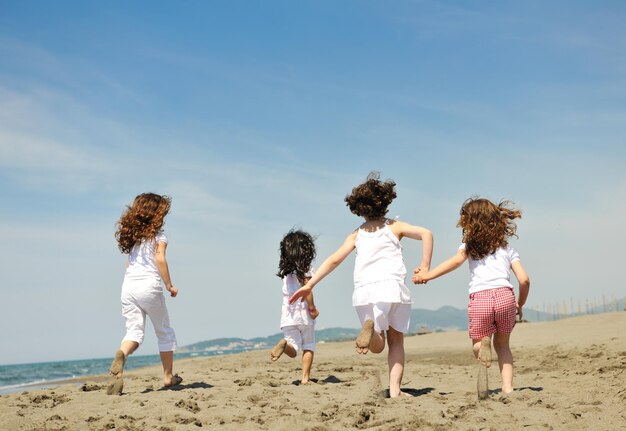 grupo de niños felices en la playa que se divierten y juegan