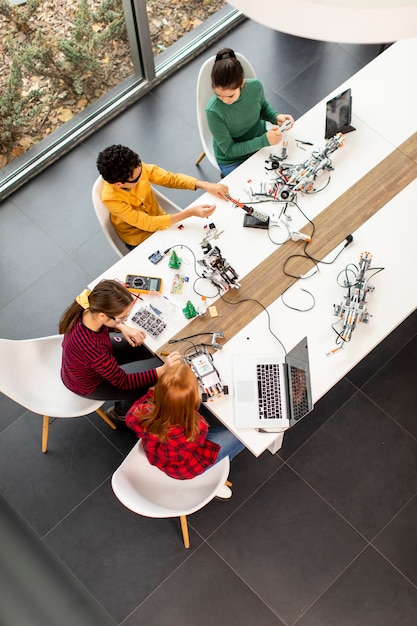 Foto grupo de niños felices que programan juguetes eléctricos y robots en el aula de robótica